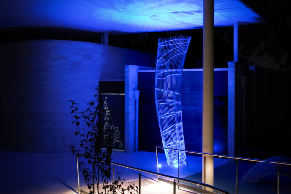 Vivid blue lighting highlights a curved semi-transparent sculpture